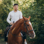 Handsome man riding a horse in forest