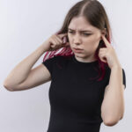 impressed young beautiful girl wearing black t-shirt closed ears on isolated white background