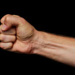 Male fist on a black background. Symbol of resistance and willpower.