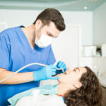 Woman Receiving Dental Treatment From Dentist In Clinic