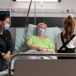 Family wearing protective face mask against covid19 while visiting sick grandmother