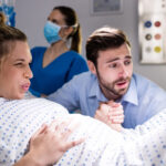 Man comforting pregnant woman during labor at hospital