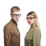 Serious young male and female employees wearing eyeglasses staring at camera with concentrated or annoyed expressions posing isolated against white copy space wall background for your information