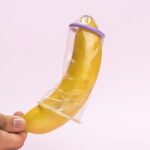 close-up-man-holding-banana-with-condom