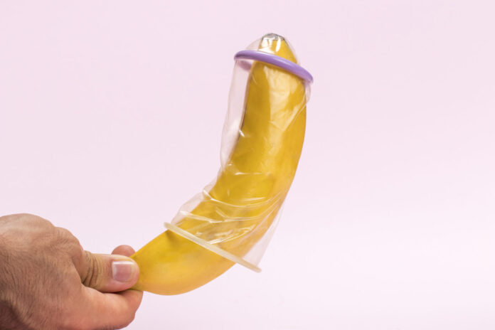 close-up-man-holding-banana-with-condom