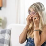 A young lady rubs her eyes because of the fatigue from wearing prescription glasses
